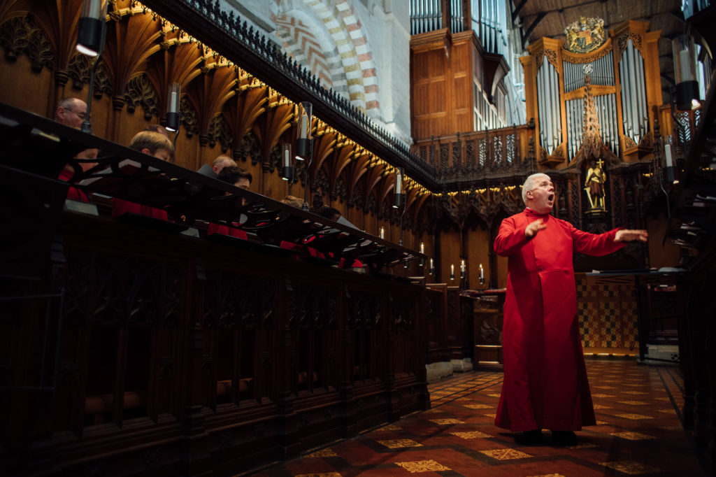 Portrait of St Albans Cathedral choir master conducting boys choir