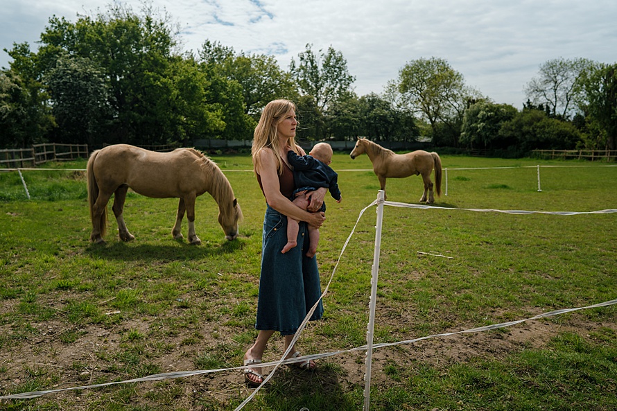 Environmental portrait of mother with child and horses Emma Collins Harpenden photographer