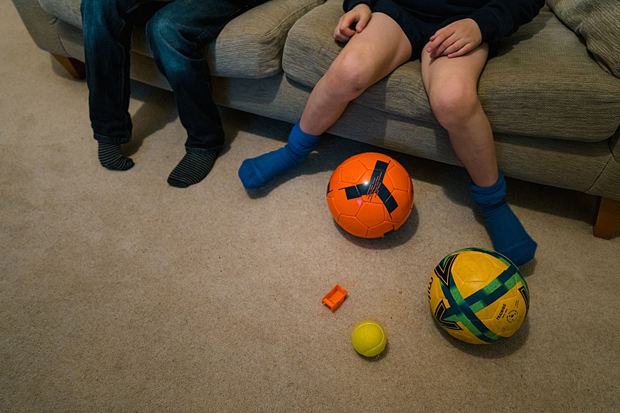Boys constantly kicking footballs even in the house on a family photoshoot in Cambridge