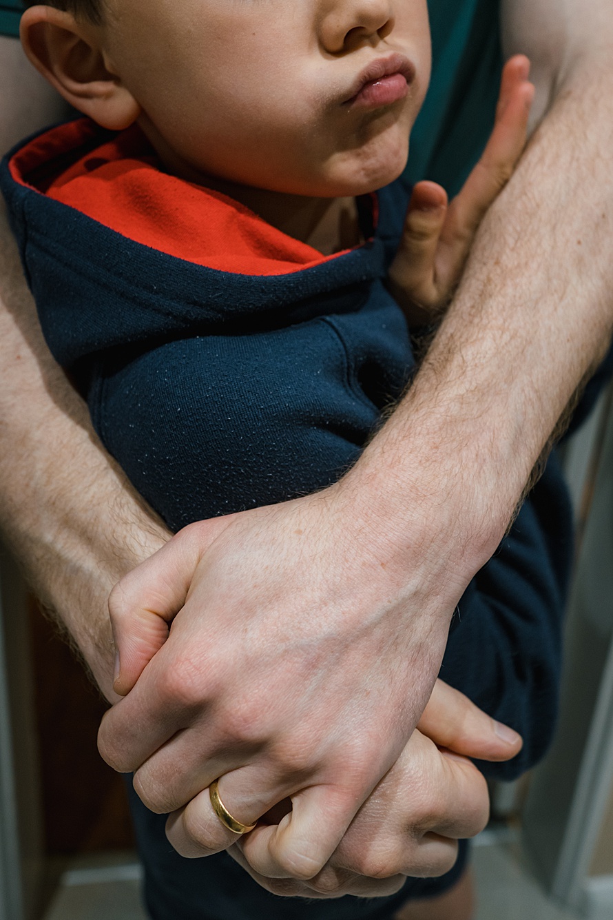 Close up photo of dad hugging son, captured by photographer Emma Collins on a day-in-the-life photoshoot in Cambridge 