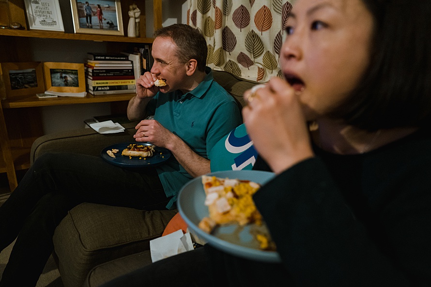 Photo of husband and wife mirroring eachother eating Pizza, documentary family photography in Cambridge 