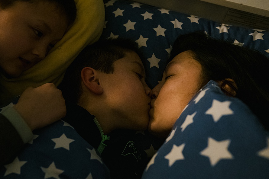 Mother kissing son goodnight at bedtime after a full day-in-the-life photoshoot in Cambridge by family documentary photographer Emma Collins