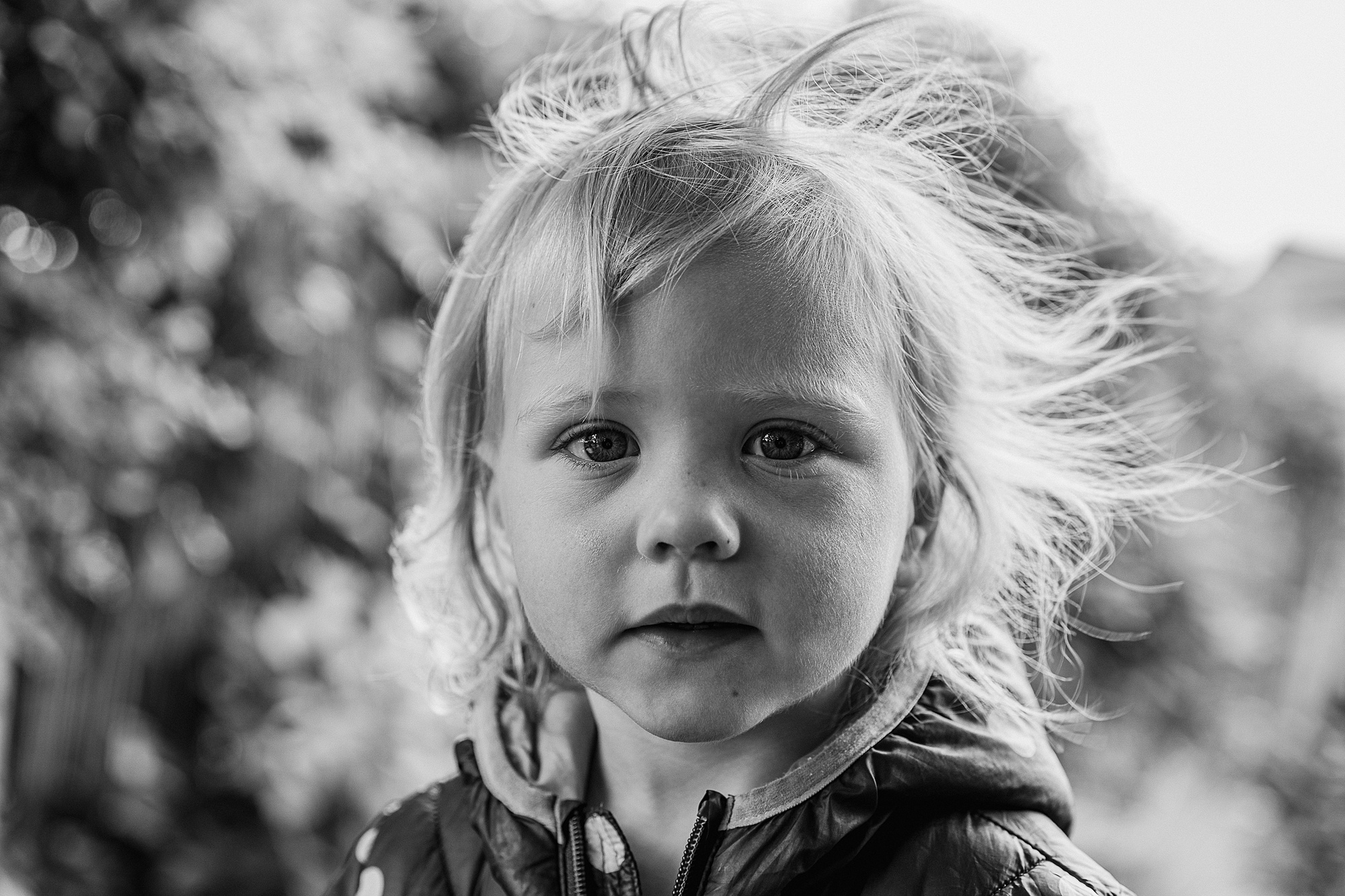 Natural black and white portrait of a little girl with hair blowing in the wind