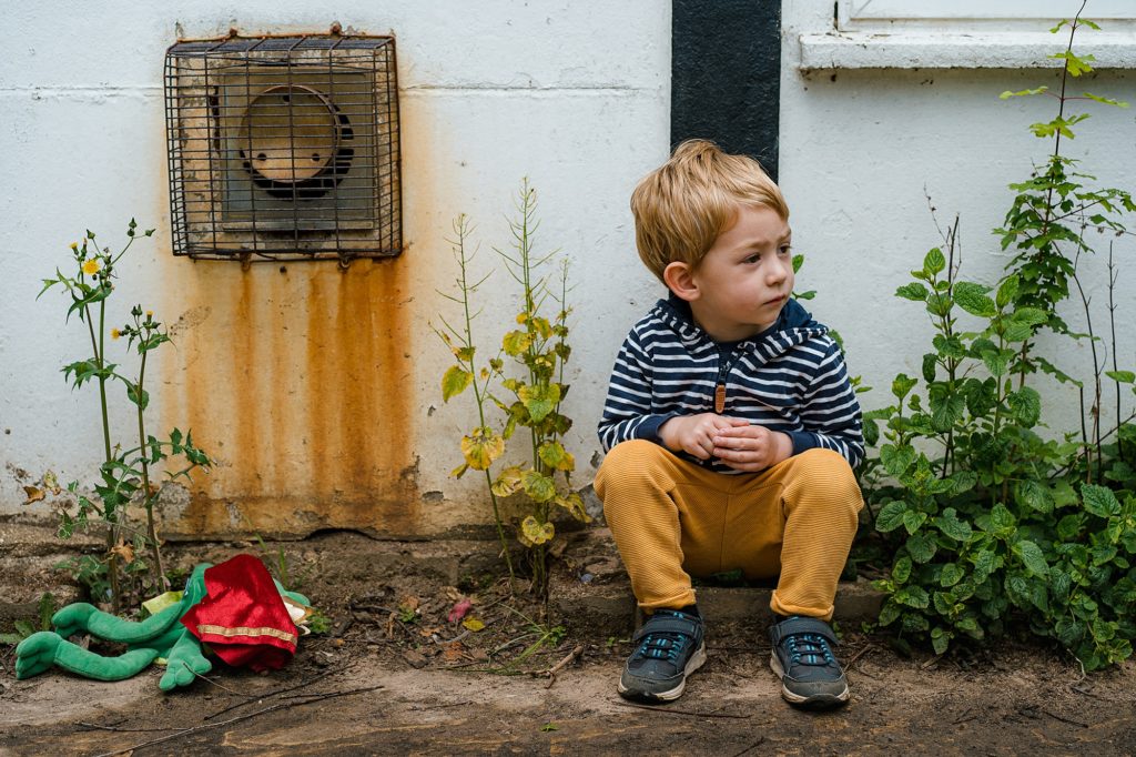 Portrait of a little boy sitting outside in a derelict yard
