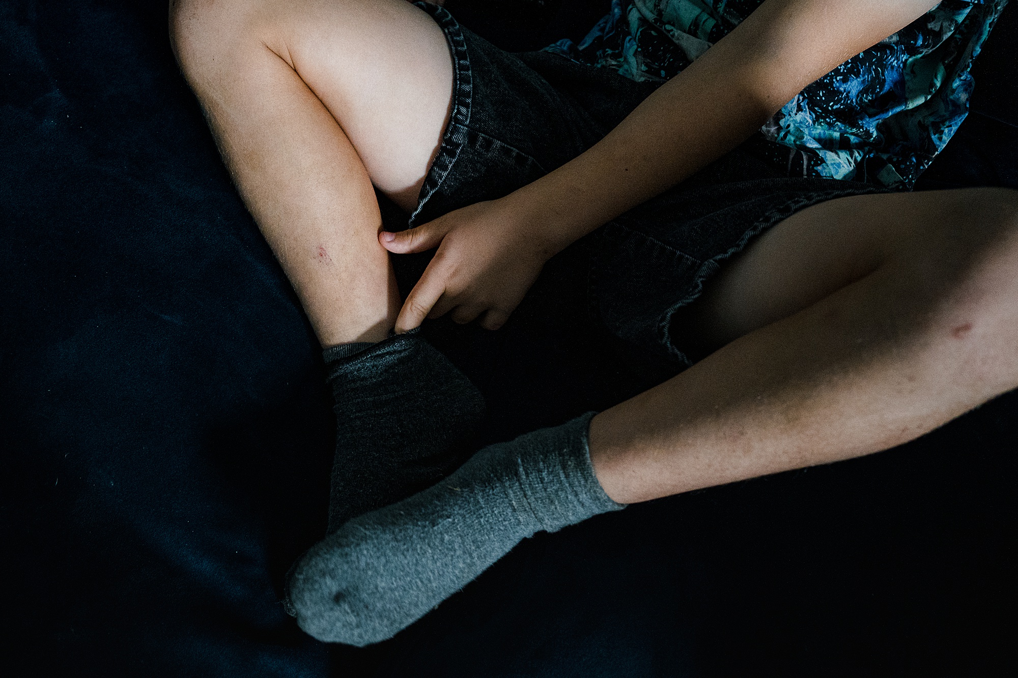 Detail of boy, dirty legs and finger in sock, reportage family photography session St Albans